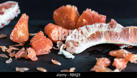 Pomelo mit rotem Fruchtfleisch vor dunklem Hintergrund Stockfoto