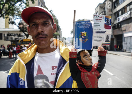 Caracas, Miranda, Venezuela. 10 Jan, 2019. Ein Mann hält die Verfassung Venezuelas und eine Puppe des Befreiers Simon Bolivar. Venezolanische Präsident Nicolas Maduro begann eine zweite Amtszeit, trotzt Kritiker in den Vereinigten Staaten und Lateinamerika Wer rief ihn ein illegitimer Usurpator einer Nation, wo wirtschaftliche Chaos getan hat, um eine humanitäre Krise. Die Nationalversammlung ruft die Maduro Regierung eine ''Diktatur und Usurpation der Macht." Derzeit ist Venezuela seine schlimmsten wirtschaftlichen Krise mit einer Inflationsrate von über 1.000.000 % (Credit Bild: © Römischen Camacho/SOPA Bilder v Stockfoto