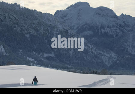 Schwangau, Deutschland. 11 Jan, 2019. Eine Frau geht durch die Winterlandschaft vor Schloss Neuschwanstein (hinten rechts). Foto: Karl-Josef Hildenbrand/dpa/Alamy leben Nachrichten Stockfoto