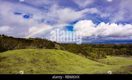 Panoramablick auf die Landschaft von Rainbow Nach einem leichten Regen und Reh ruht auf den Hügeln von Rancho San Antonio County Park, South San Francisco, Calif Stockfoto