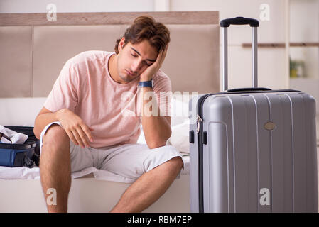 Mann mit Koffer im Schlafzimmer warten auf Reise Stockfoto