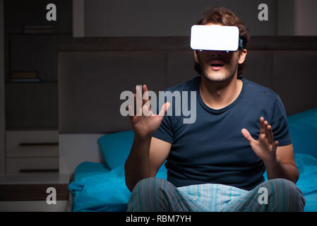 Junger Mann Spielen von Computerspielen in der Nacht im Bett Stockfoto