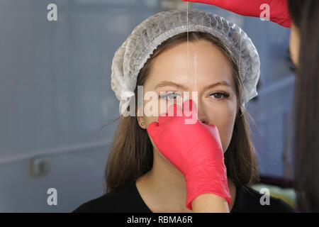 Brauen korrigieren. Markierungslinien für perfekte Form der Augenbrauen zu erstellen. Arbeit von Meister cosmetologist. Stockfoto