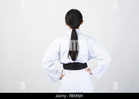 Junge Frau mit Karate Anzug zurück auf weißem Hintergrund Stockfoto