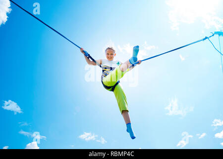 Kleines Mädchen springt hoch in die Luft mit einem Bungee Trampolin. Stockfoto