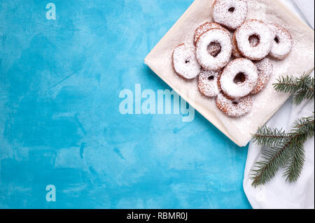 Süße Krapfen auf einer Platte, auf weissem leinen Serviette befindet. Mit einem Zweig der Tannenbaum geschmückt. Bild mit Platz für Text. Horizontale Ausrichtung. Stockfoto