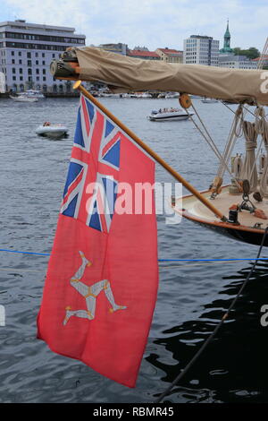 Eine Fahne mit der Zivilgesellschaft, der Stern der Insel Man, bestehend aus einem triskelion und eine Union Jack, auf den Bogen von einem Segelboot Hafen in Bergen, Norwegen. Stockfoto