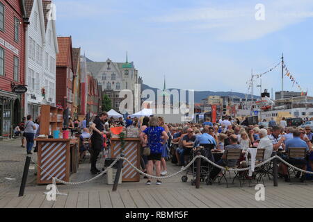 Die Leute sitzen in einem Café im Freien auf dem UNESCO-Weltkulturerbe Bryggen, während der traditionelle Markt Tag (Torgdagen) in Bergen, Norwegen. Stockfoto