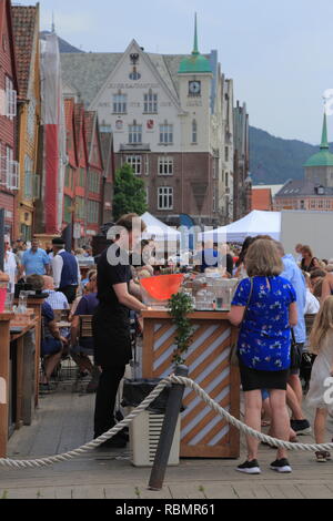 Ein Mann bedient Kunden an einer im Restaurant- und Barbereich auf der UNESCO-Welterbestätte Bryggen, während der Markt Tag in Bergen, Norwegen. Stockfoto