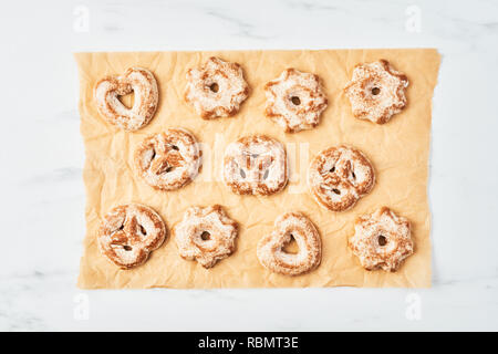 Frisch gebackene Weihnachten Lebkuchen Kekse mit Zuckerguss auf Pergament- oder Backpapier über weißem Marmor tisch. Ansicht von oben. Kopieren Sie Platz für Text. Stockfoto