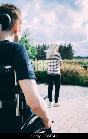 Mann mit dystonie im Rollstuhl und Frau in Beziehung Kampf Stockfoto