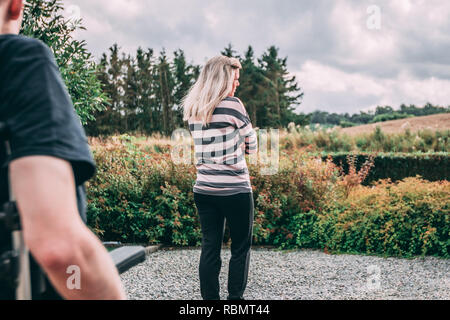 Mann mit dystonie im Rollstuhl und Frau in Beziehung Kampf Stockfoto