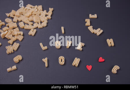 Text Ich liebe dich mit Makkaroni in Form von Buchstaben auf schwarzem Holz- Tabelle geschrieben Stockfoto