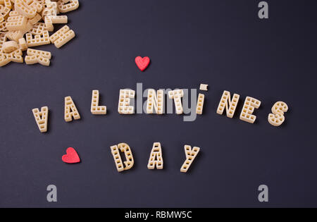 Text Valentines Tag mit Makkaroni in Form von Buchstaben auf schwarzem Holz- Tabelle geschrieben Stockfoto