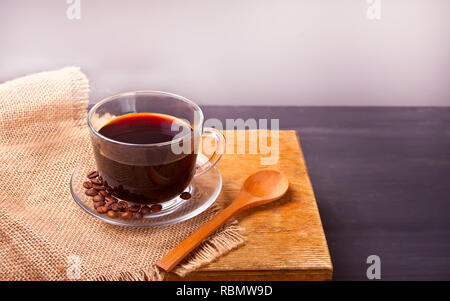Tasse Kaffee und Kaffeebohnen auf dem hölzernen Tisch Stockfoto