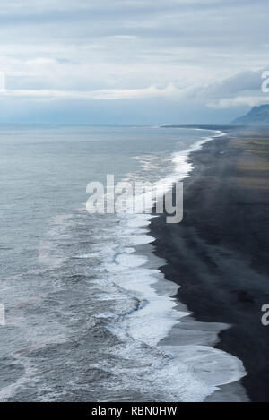 Luftaufnahme der endlosen Küste mit Überspannungsschutz und dunklen Strand Stockfoto