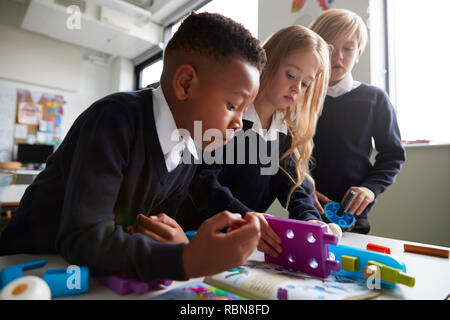 Nahaufnahme von drei Grundschüler gemeinsam mit Spielzeug Bau Blöcke in einem Klassenzimmer, niedrigen Winkel, Seitenansicht Stockfoto