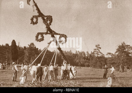 Mittsommer Tradition in den 1930er Jahren. Als Teil der Festlichkeiten einen Maibaum ist auferstanden und hier eine Gruppe von Menschen steigt die Pole vor Beginn um ihn zu tanzen. Schweden 1930. Stockfoto