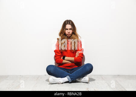 Volle Länge Foto von umgekippt Frau 20 s legere Kleidung Sitzen mit gekreuzten Beinen auf dem Boden und nachtragend Blick auf weißem Hintergrund Stockfoto