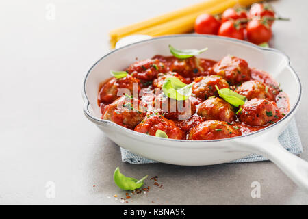 Hausgemachte Frikadellen mit Tomaten und Gewürzen serviert pan in Weiß auf grauem Hintergrund. Nahaufnahme. Stockfoto
