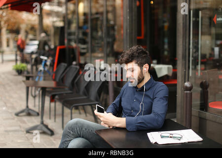 American Boy Musik im Cafe mit Ohrhörer und smart Stockfoto