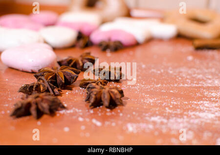 Weihnachten Lebkuchen mit weißen und rosa Zuckerglasur und Sternanis auf einer hölzernen Küchentisch Stockfoto