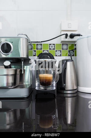 Kleine Kaffeemaschine macht den Espresso Kaffee mit den Kapseln die oben auf der counter Bar in der Küche. Stockfoto