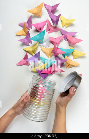 Weibliche Hände öffnen Jar mit Papier Schmetterlinge auf weißem Hintergrund. Origami Stockfoto