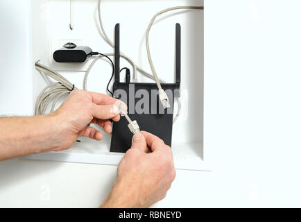 Anschluss von Wi-Fi-Router mit dem Internet. Die menschliche Hand am Kabel und Stecker. Stockfoto