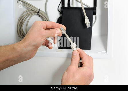 Anschluss von Wi-Fi-Router mit dem Internet. Die menschliche Hand am Kabel und Stecker. Stockfoto