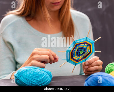 Junge Mädchen tut Handarbeit Mandala aus farbigen Garnen. Junge Frau beteiligt sich an der Werkstatt. Stockfoto