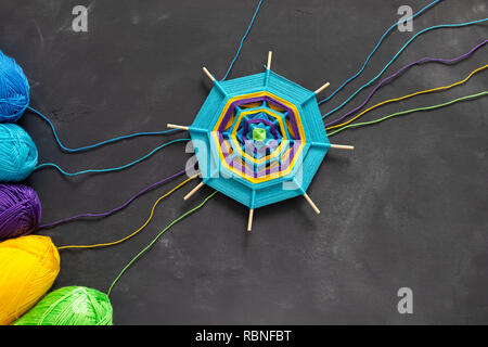 Farbige Handarbeit Mandala und bunten Fäden auf dunkelgrauem Hintergrund. Stockfoto