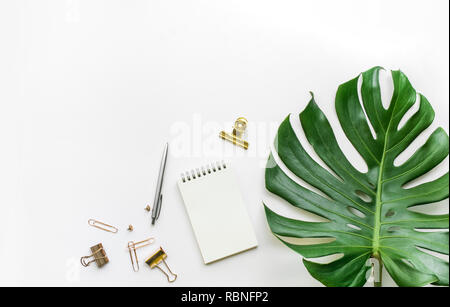 Blick von oben auf die Business Schreibtisch Tisch mit monstera Blätter und Mock up Zubehör auf weißem Hintergrund. Flaches Design legen. Kopieren Sie Platz Stockfoto