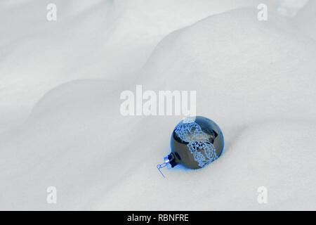 Ein blauer Christbaumschmuck liegt in ein Bett aus Schnee Stockfoto