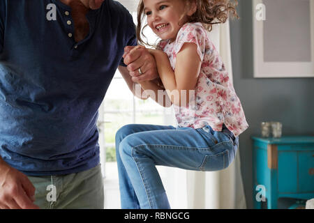 Mädchen springen auf und Halten der Papa zu Hause, mittlere Partie Stockfoto