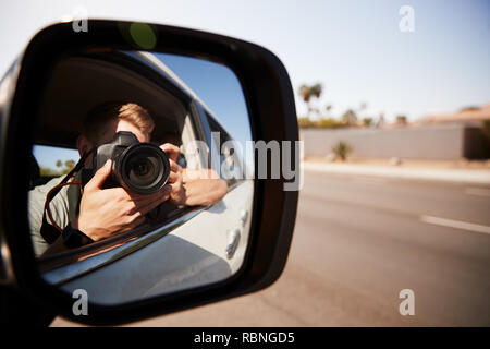 Junger Mann in Auto, Foto, im Rückspiegel gesehen Stockfoto