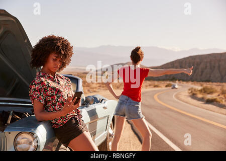 Zwei weibliche Freunde durch Ihre aufgeschlüsselt Auto am Straßenrand Stockfoto