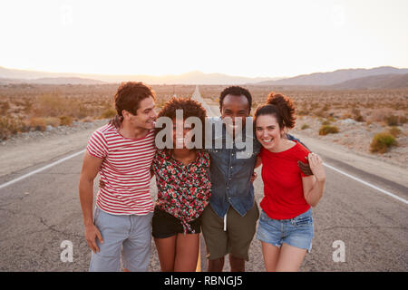 Vier glückliche Freunde stehen auf einer einsamen Landstraße, in der Nähe Stockfoto