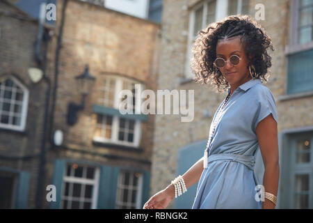 Trendy Frau in Blau angeschnittene Ärmel Kleid und Sonnenbrille Stockfoto