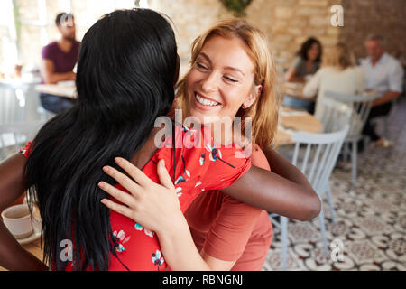 Zwei junge weibliche Freunde umarmen in einem Cafe, in der Nähe Stockfoto