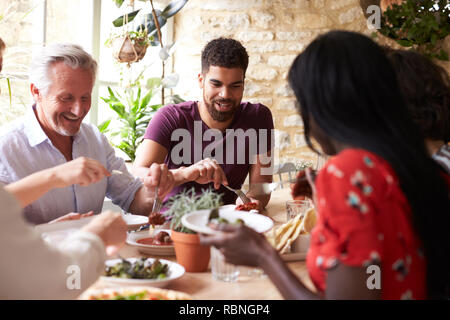 Lächelnd Freunde zusammen essen an einem Tisch in einem Cafe Stockfoto