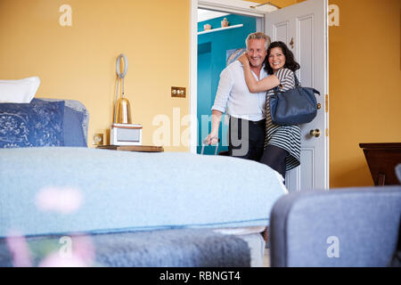 Paar mittleren Alters umarmen in der Tür von einem Hotel Zimmer Stockfoto