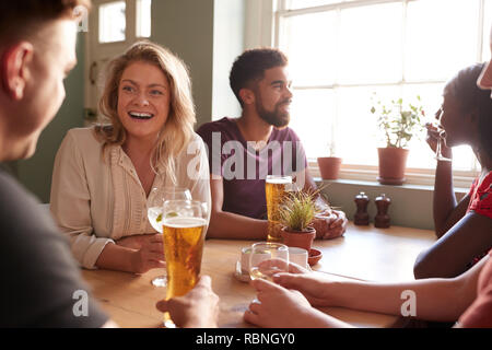 Junge Erwachsene Freunde reden an einem Tisch in einer Kneipe Stockfoto