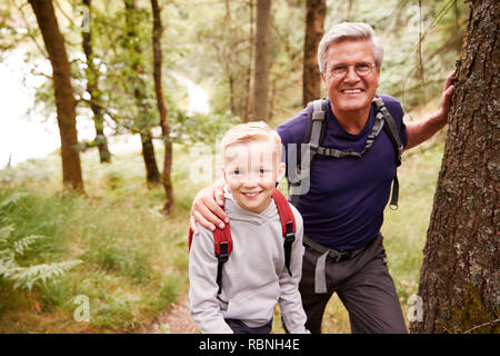 Großvater und Enkel eine Pause während Gemeinsam wandern im Wald, in der Nähe, ein Lächeln für die Kamera Stockfoto