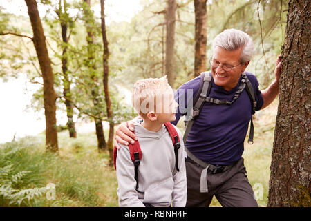 Großvater und Enkel eine Pause während Gemeinsam wandern im Wald, in der Nähe, an jedem anderen Suchen Stockfoto