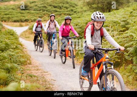 Pre-teen Boy reiten Mountainbike mit seiner Schwester und Eltern während einer Familie camping Reise, in der Nähe Stockfoto