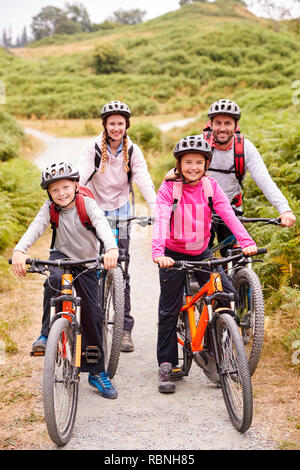 Eltern und Kinder sitzen auf Mountainbikes in einem Feldweg während einer Familie Camping Trip, volle Länge Stockfoto