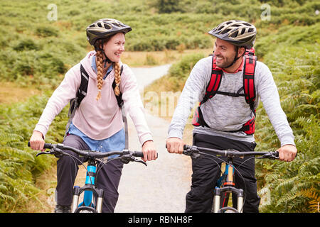 Junge Erwachsene paar Riding Mountain bikes in einem Feldweg, jeder andere, in der Nähe Stockfoto