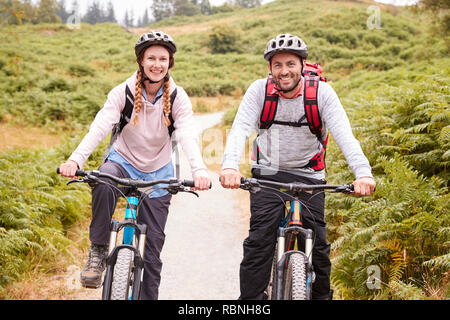 Junge Erwachsene paar Riding Mountain bikes in einem Feldweg, an der Kamera suchen, Nahaufnahme Stockfoto