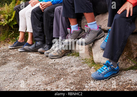 Nahaufnahme von Schlammigen Schuhe und Hose aus einer Familie sitzt auf den Steinen am See, Detail Stockfoto